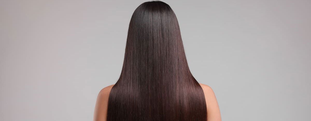 Imagem de uma mulher de cabelo liso, vista de costas.