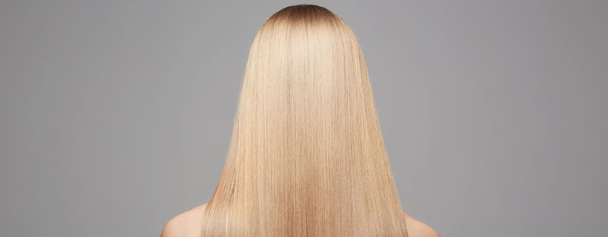 Imagem de uma mulher loira de cabelo liso vista de trás.