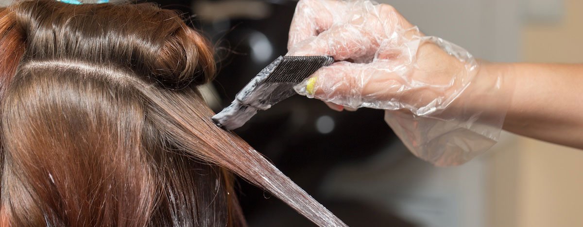 Imagem de uma mulher a fazer madeixas no cabelo num salão de cabeleireiro.