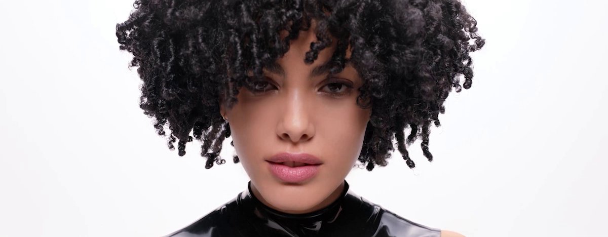 O foco está em várias mulheres com diferentes tipos de cabelo encaracolado, apresentando a rotina de cuidados capilares da L’Oréal para cada tipo de caracol.