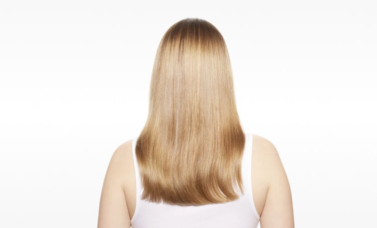 Mulher com o cabelo visivelmente reparado, apresentando maior força, suavidade e brilho após seguir o guia definitivo para reparar o cabelo danificado.
