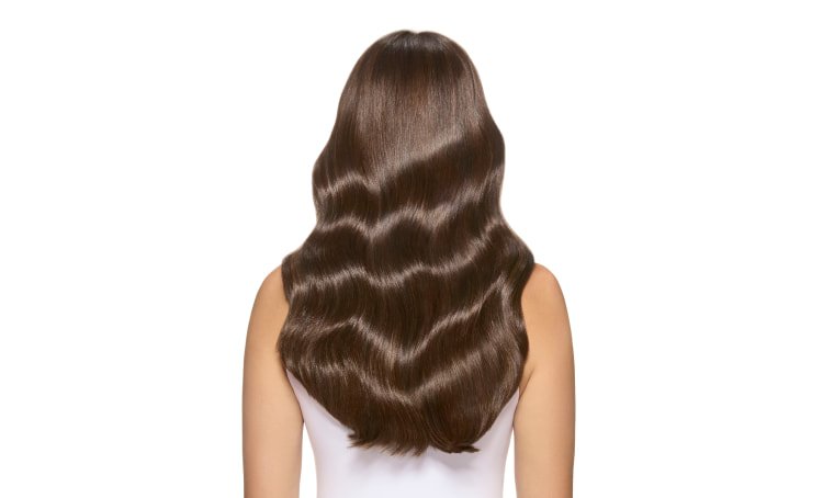 Mulher de pé sobre um fundo intergaláctico desértico, exibindo a cor vibrante do seu cabelo, um tom bronze titânio, e a sua identidade marcante.