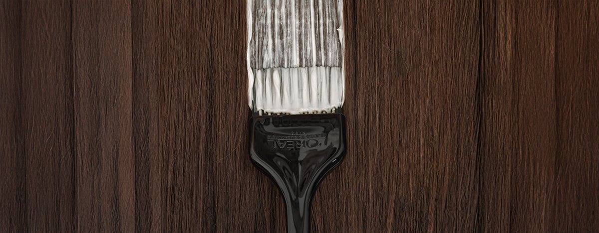 Observe atentamente um pincel profissional de salão a aplicar coloração no cabelo, ilustrando as técnicas utilizadas para cobrir eficazmente os cabelos brancos.