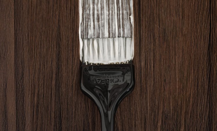 Observe atentamente um pincel profissional de salão a aplicar coloração no cabelo, ilustrando as técnicas utilizadas para cobrir eficazmente os cabelos brancos.