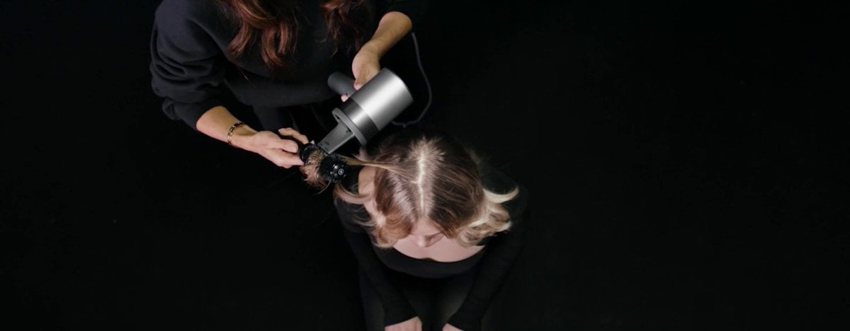 Demonstração de uma mulher a secar o cabelo com o secador L’Oréal Air Light Pro, sem danos graças à sua tecnologia protetora.