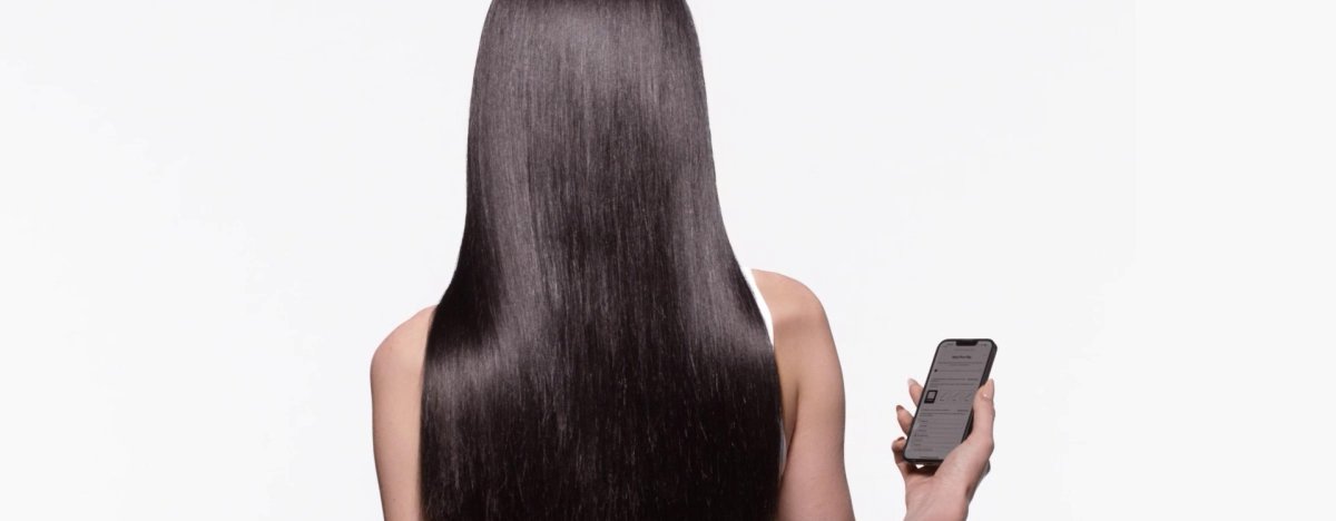Mulher com longos cabelos castanhos brilhantes utiliza um diagnóstico capilar online para escolher os produtos mais adequados para a sua rotina de cuidados capilares.